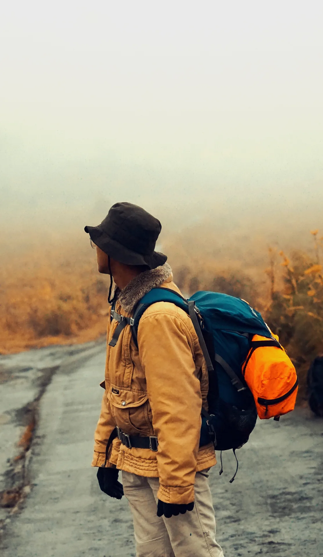 Side portrait of a traveller with an orange backpack looking across the Bromo landscape
