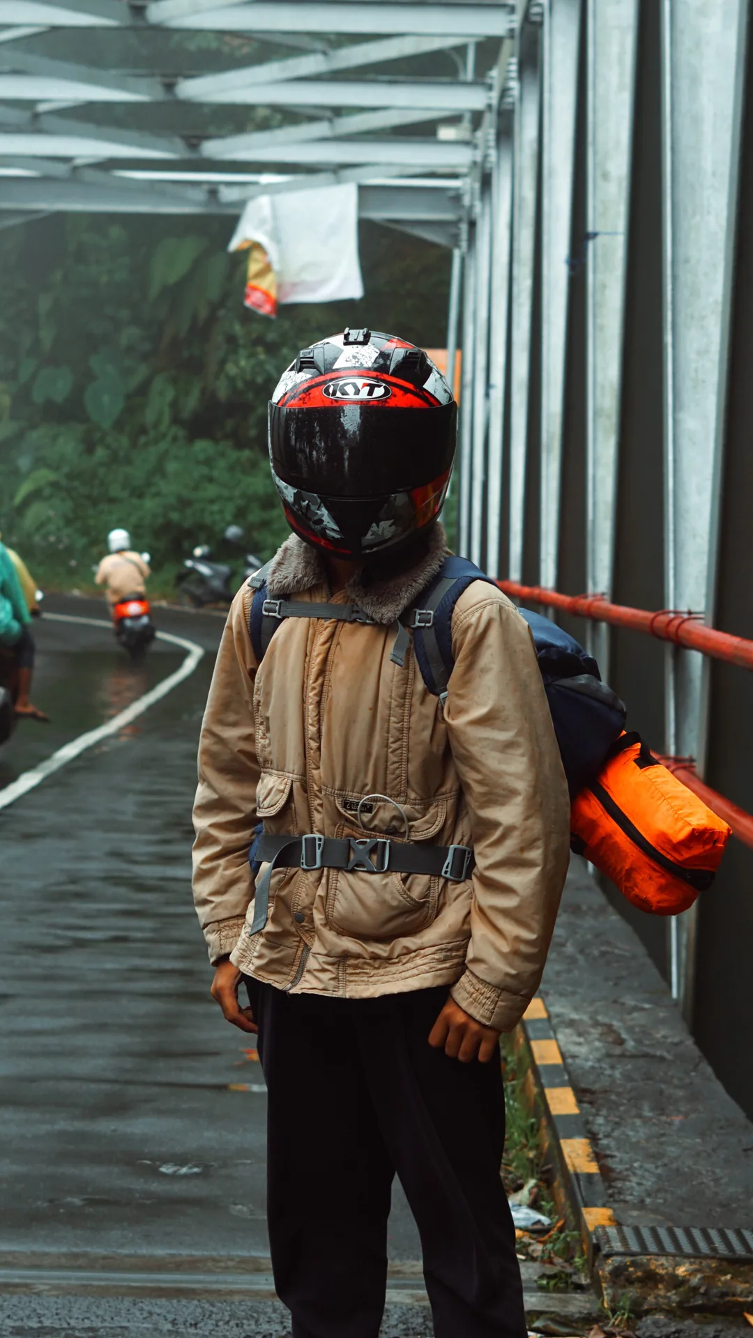 Motorcyclist in riding gear standing on a steel bridge in Cangar