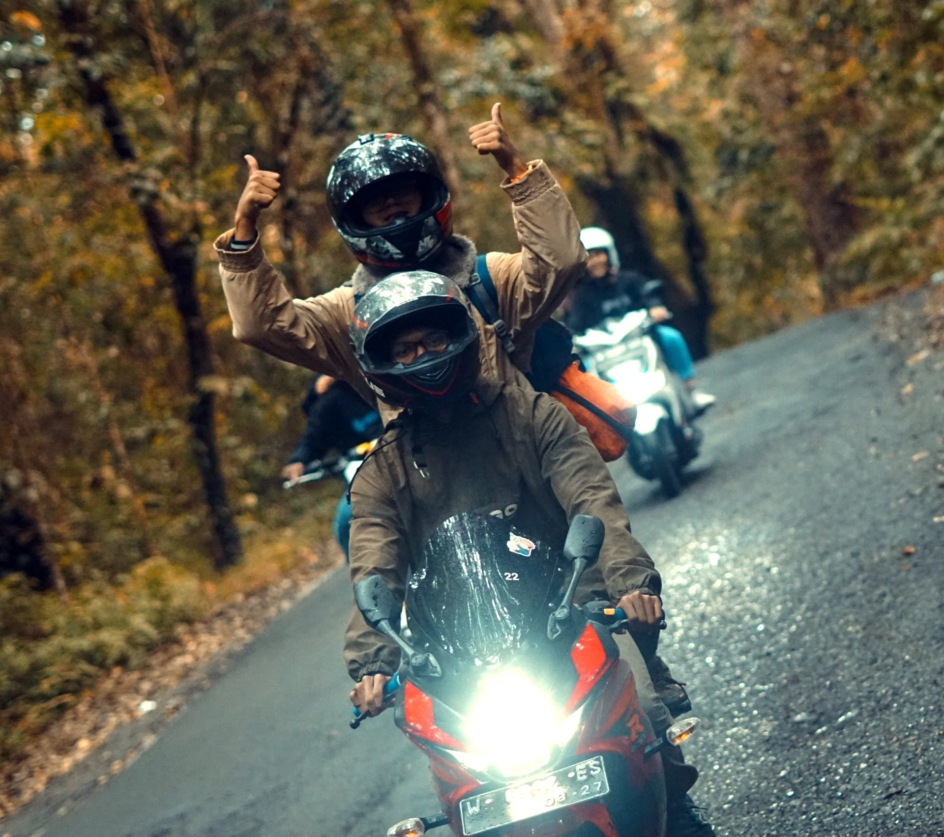 Group of motorcyclists riding along a winding forest road in Cangar