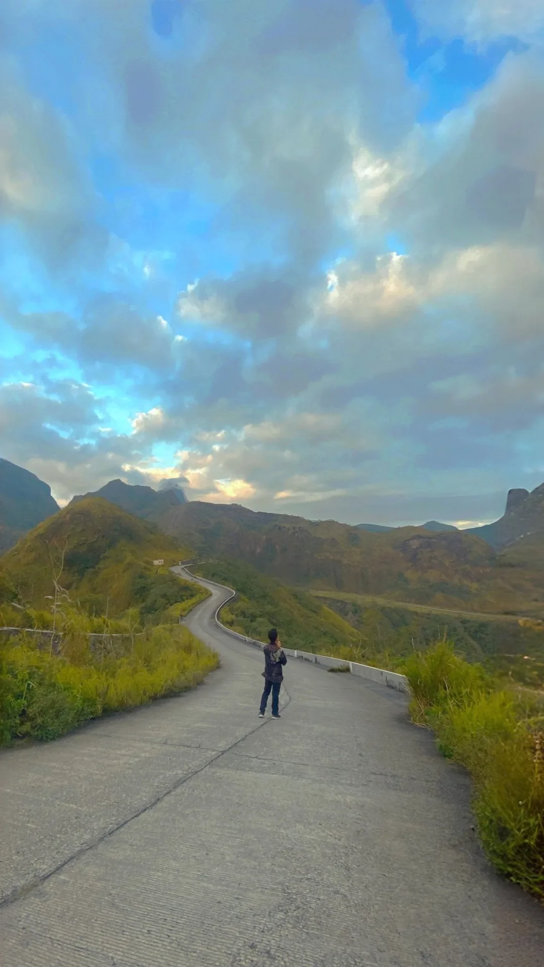 A lone traveller walking along a winding road through the Mount Kelud landscape
