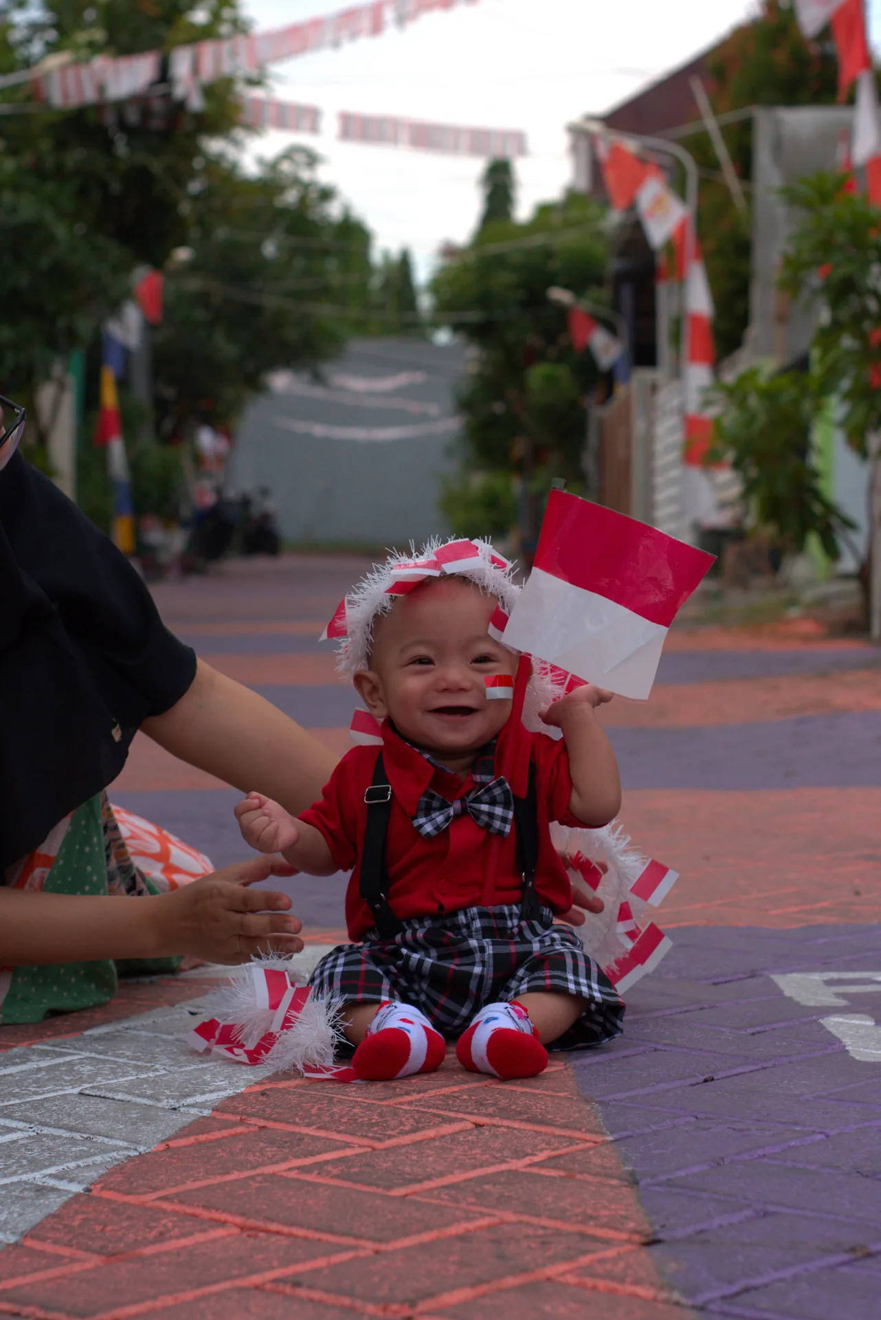 Full portrait of Azel seated on a colourful street with Indonesian flags
